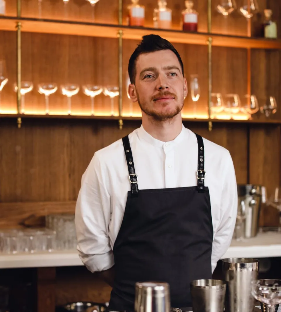 A bartender with his hands on his back